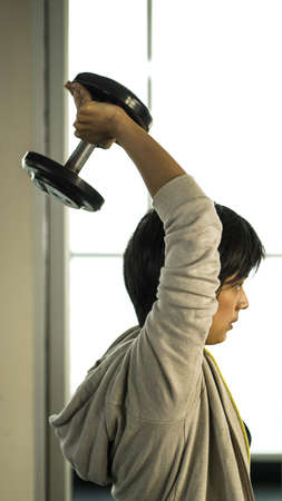 Smiling Asian short hair woman fitness dumbbell lifting. Healthy exerciseの写真素材