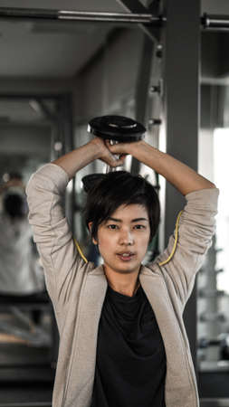 Smiling Asian short hair woman fitness dumbbell lifting. Healthy exerciseの写真素材
