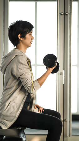 Smiling Asian short hair woman fitness dumbbell lifting. Healthy exerciseの写真素材