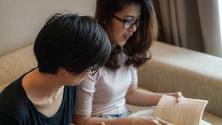 Two Asian woman friends reading books and have fun discussion on hobbyの写真素材
