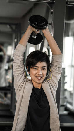 Smiling Asian short hair woman fitness dumbbell lifting. Healthy exerciseの写真素材