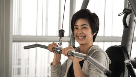 Asian woman fitness training machine smile faceの写真素材