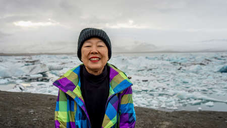 Asian old woman happy at Jokulsarlon glacier lagoon, Iceland
