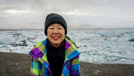 Asian old woman happy at Jokulsarlon glacier lagoon, Icelandの写真素材