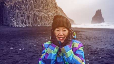Asian senior woman having drean trip travel to Icealand, black beachの写真素材