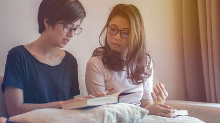 Two Asian woman friends reading books and have fun discussion on hobby