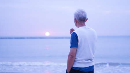 Asian senior man standing alone at sunrise morningの写真素材