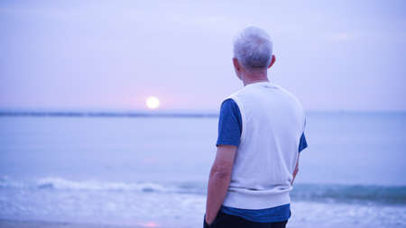 Asian senior man standing alone at sunrise morning
