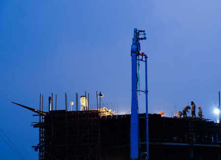 Construction crane truck working on structure at night with lightの写真素材