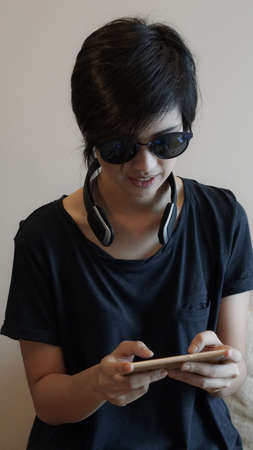 Asian woman hipster lifestyle using smartphone while using headphones and wearing eyeglassesの写真素材