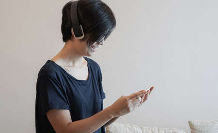 Asian woman hipster lifestyle using smartphone while using headphones and wearing eyeglassesの写真素材