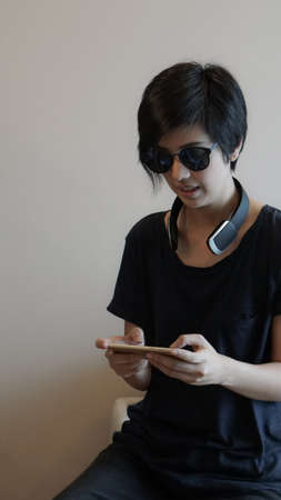 Asian woman hipster lifestyle using smartphone while using headphones and wearing eyeglassesの写真素材
