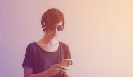 Asian woman hipster lifestyle using smartphone while using headphones and wearing eyeglassesの写真素材