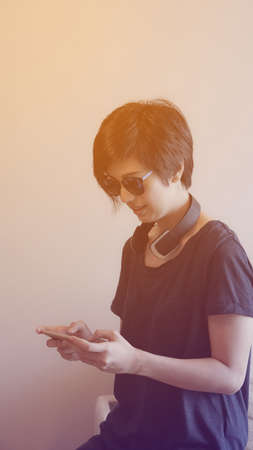 Asian woman hipster lifestyle using smartphone while using headphones and wearing eyeglassesの写真素材
