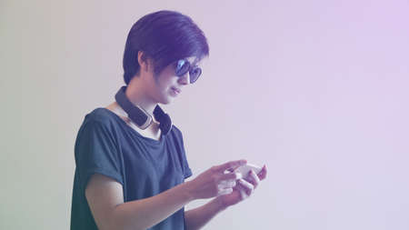 Asian woman hipster lifestyle using smartphone while using headphones and wearing eyeglassesの写真素材