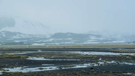 Iceland extreme bad weather snow and fog mountaitn background, green moss fieldの写真素材