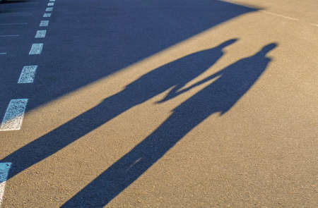 Couple shadow holding hand on road tripの写真素材