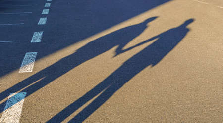 Couple shadow holding hand on road tripの写真素材