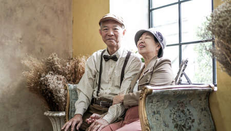 Asian senior couple dress vintage retro style in luxury house with tuscan style yellow wallの写真素材