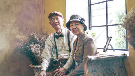 Asian senior couple dress vintage retro style in luxury house with tuscan style yellow wallの写真素材