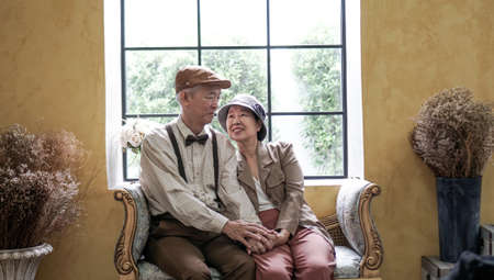 Asian senior couple dress vintage retro style in luxury house with tuscan style yellow wallの写真素材