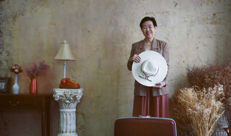Asian senior woman vintage retro fashion with travel luggage luxury retriement lifeの写真素材