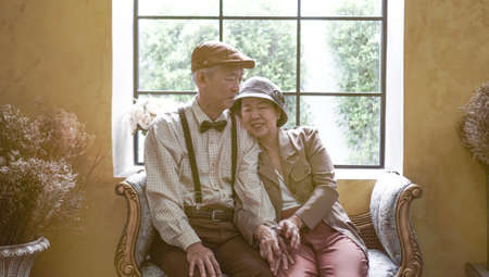 Asian senior couple dress vintage retro style in luxury house with tuscan style yellow wallの写真素材
