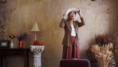 Asian senior woman vintage retro fashion with travel luggage luxury retriement lifeの写真素材
