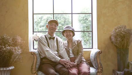 Asian senior couple dress vintage retro style in luxury house with tuscan style yellow wallの写真素材