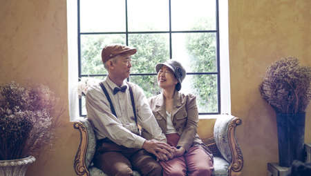 Asian senior couple dress vintage retro style in luxury house with tuscan style yellow wallの写真素材