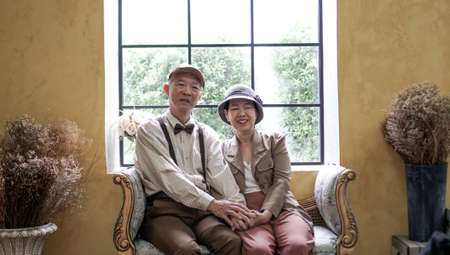 Asian senior couple dress vintage retro style in luxury house with tuscan style yellow wallの写真素材