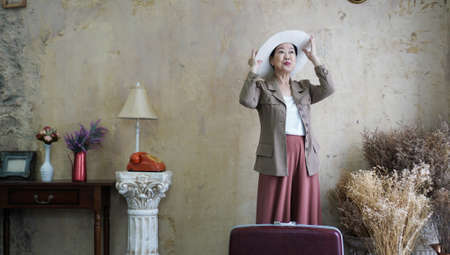 Asian senior woman vintage retro fashion with travel luggage luxury retriement lifeの写真素材