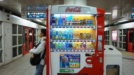 Osaka, Japan : 4 March 2015 - Woman stand next to vendor machine in Japan rail station aloneのeditorial素材