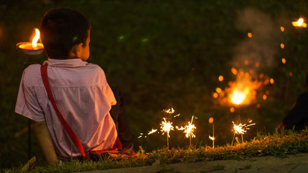 boy sit and play firework next to riverのeditorial素材