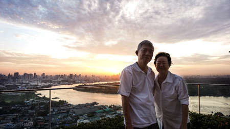 Asian senior couple with morning sunrise on luxury condominium in Thailand