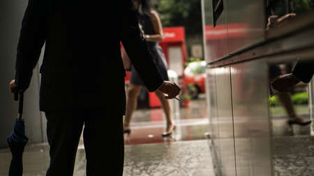 Businessman smoking after stress break from work in office, busy raining city background
