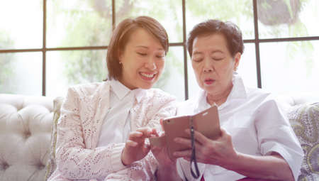 Daugther teaching mother to use smart phone for social mediaの写真素材