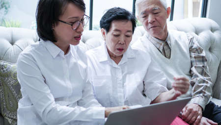Asian senior couple consult and discuss health plan with woman doctor at homeの写真素材