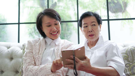 Daugther teaching mother to use smart phone for social mediaの写真素材