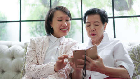 Daugther teaching mother to use smart phone for social mediaの写真素材