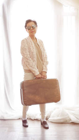 Asian senior woman travel with vintage luggage in luxury hotel resortの写真素材