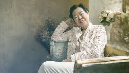 Asian senior woman sit in beautiful luxury interior room tuscan vintage styleの写真素材