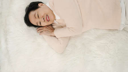 Asian senior woman wear pink sweater sleep on fur bedの写真素材