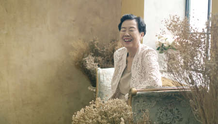 Asian senior woman sit in beautiful luxury interior room tuscan vintage styleの写真素材