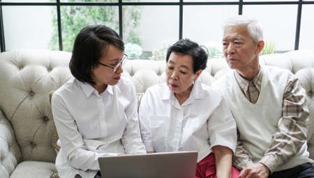 Asian senior couple consult and discuss health plan with woman doctor at homeの写真素材