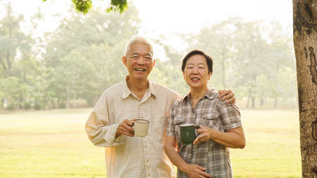 Asian elderly couple drink tea coffee in moring parkの写真素材