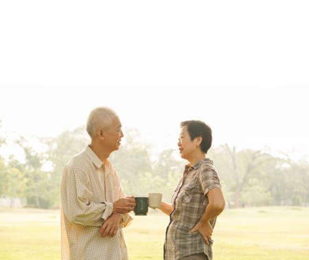 Asian elderly couple drink tea coffee in moring parkの写真素材