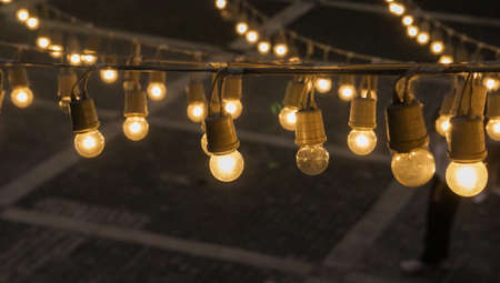 Festival garland light bulbs hanging over outdoor  shopping area copy spaceの写真素材
