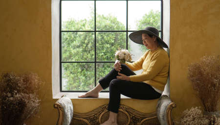 Asian senior woman sit in Europe style window summer sunlight, luxury travelの写真素材