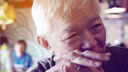 Asian senior man listen happily positive vibe in restaurantの写真素材